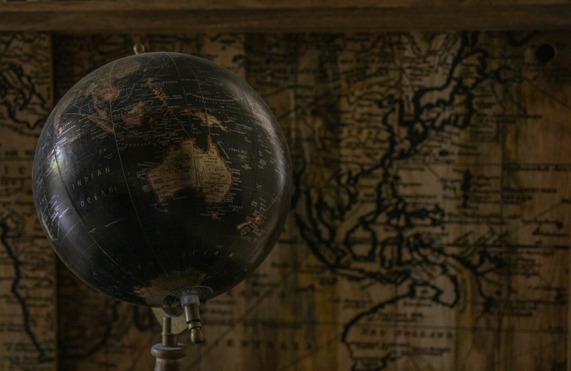 a black and brown globe on a stand in front of a map